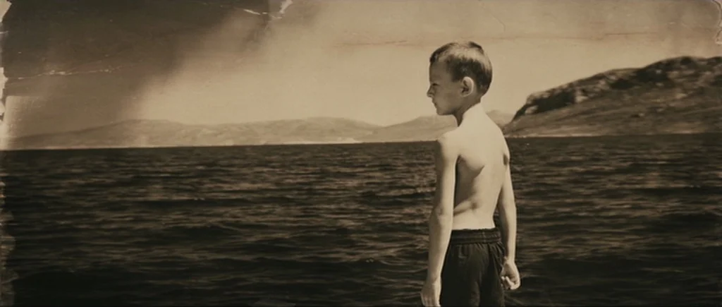 Once Upon a Time in Anatolia (2011) movie still: medium — A shirtless boy stands by a body of water with distant hills in view. The frame has a…
