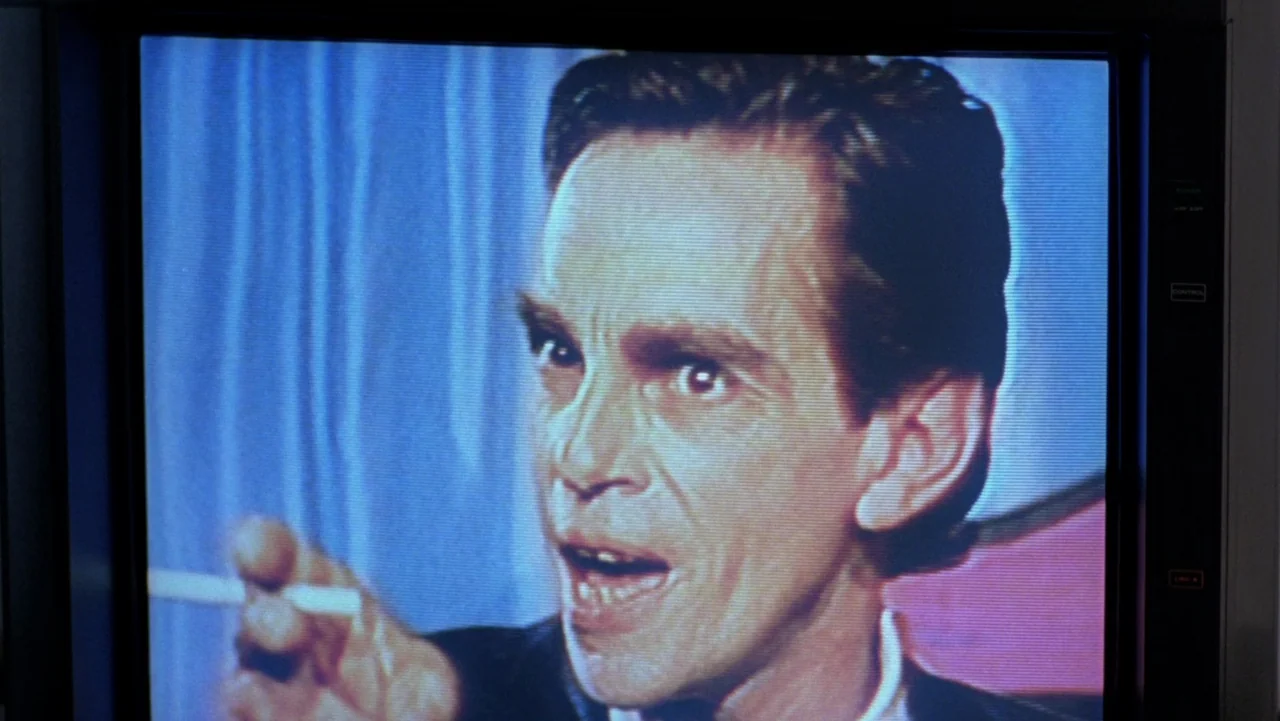 Frankenhooker (1990) movie still: closeup — A close-up view of a television monitor displaying a broadcast of a man. The image is distorted by…