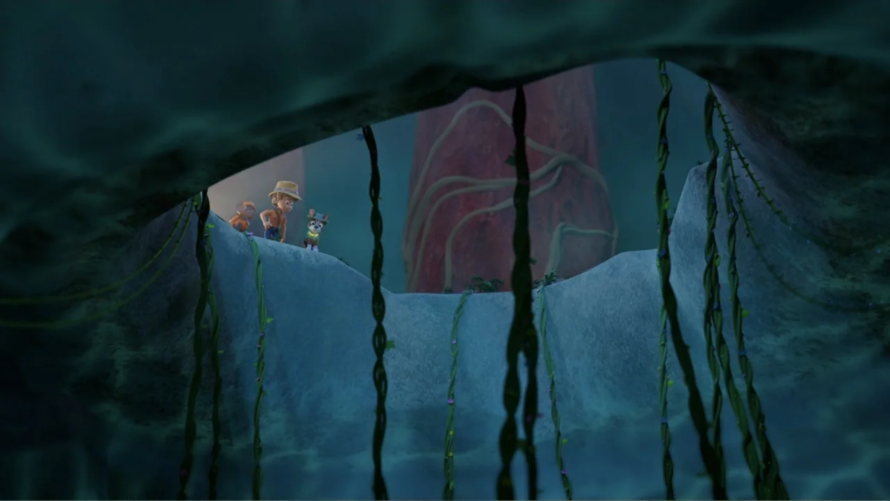 Valiente: A Tracker Story (2025) movie still: wide — A dark cave entrance is framed by hanging vines and textured stone walls. A young boy in a hat…