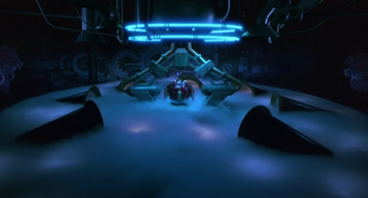 Explorers (1985) movie still: wide — A dark, dimly lit laboratory filled with thick white fog on a circular platform. A mechanical red orb sits…