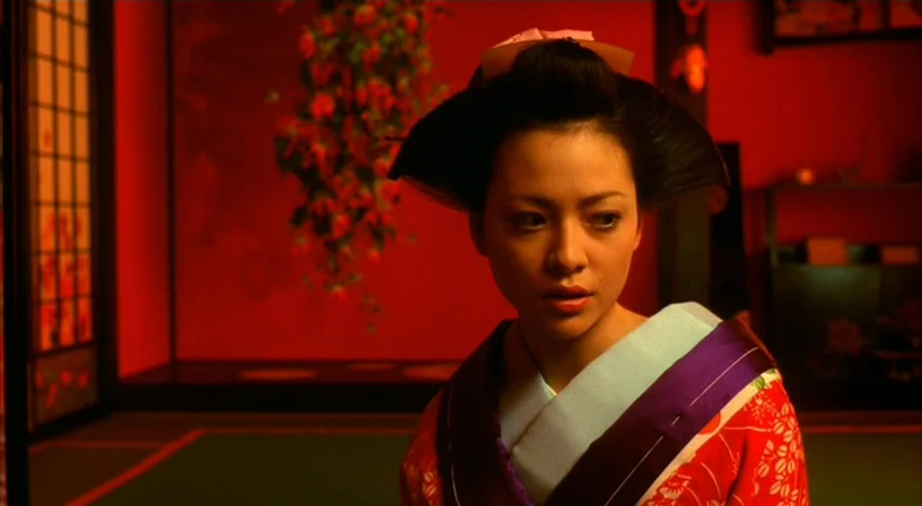 Sakuran (2006) movie still: medium — A dark, red-lit space features traditional Japanese decor and a sliding paper screen. A woman in a floral…