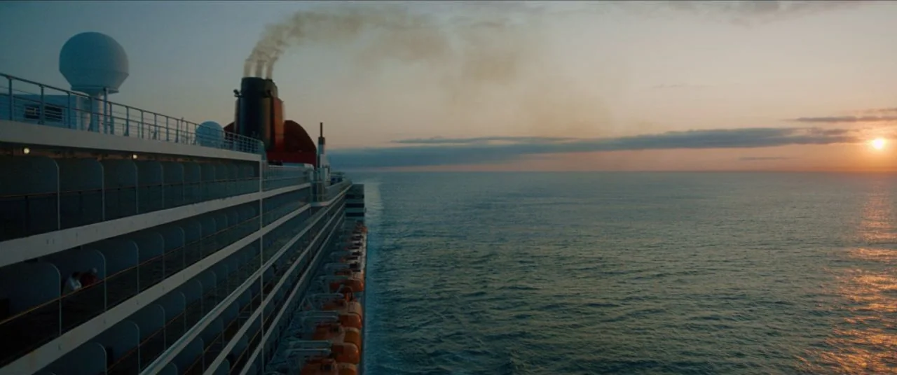 Let Them All Talk movie still: wide — A side view of a large cruise ship steaming across the open ocean. Smoke trails from the vessel's dark funnel…