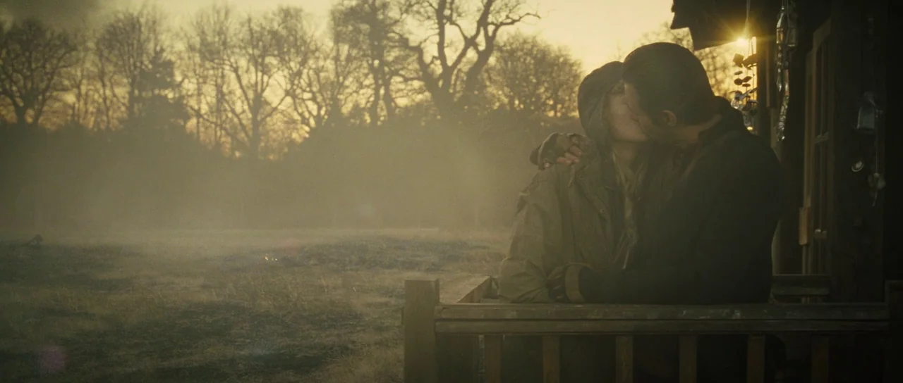 The World’s End (2013) movie still: medium — Two individuals sit on a wooden porch during a hazy golden hour sunset. They are silhouetted against a…