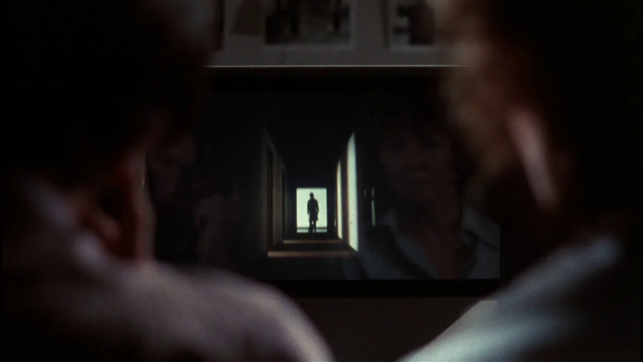 Star 80 (1983) movie still: medium — Two individuals sit in a dark room facing a glowing television set. The television screen displays a…