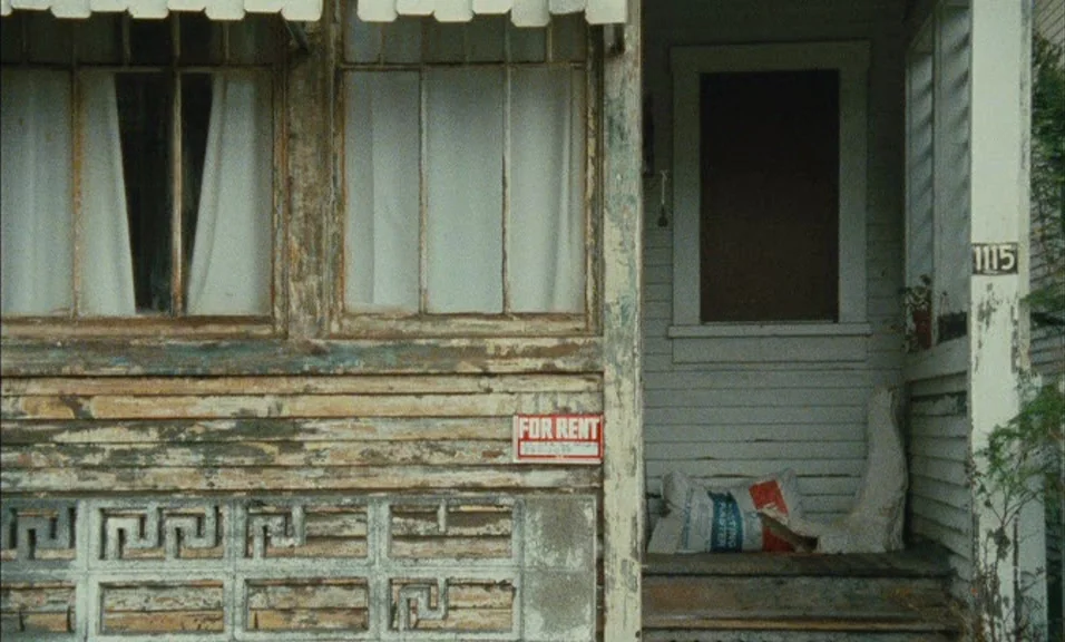 Documenteur (1981) movie still: medium — A weathered wooden house exterior shows peeling paint and an old Greek key pattern.