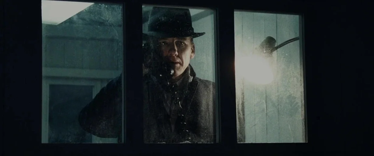 Bridge of Spies (2015) movie still: medium — A man stands inside a glass telephone booth at night during a rainstorm. He holds the telephone…